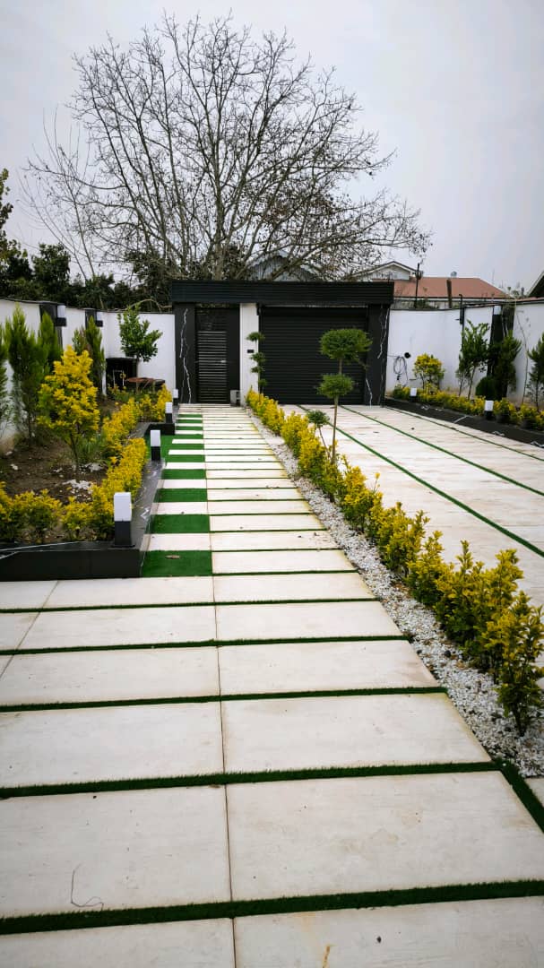 تصویر یک ویلای نما مدرن و محوطه سازی شده با موزاییک و چمن مصنوعی