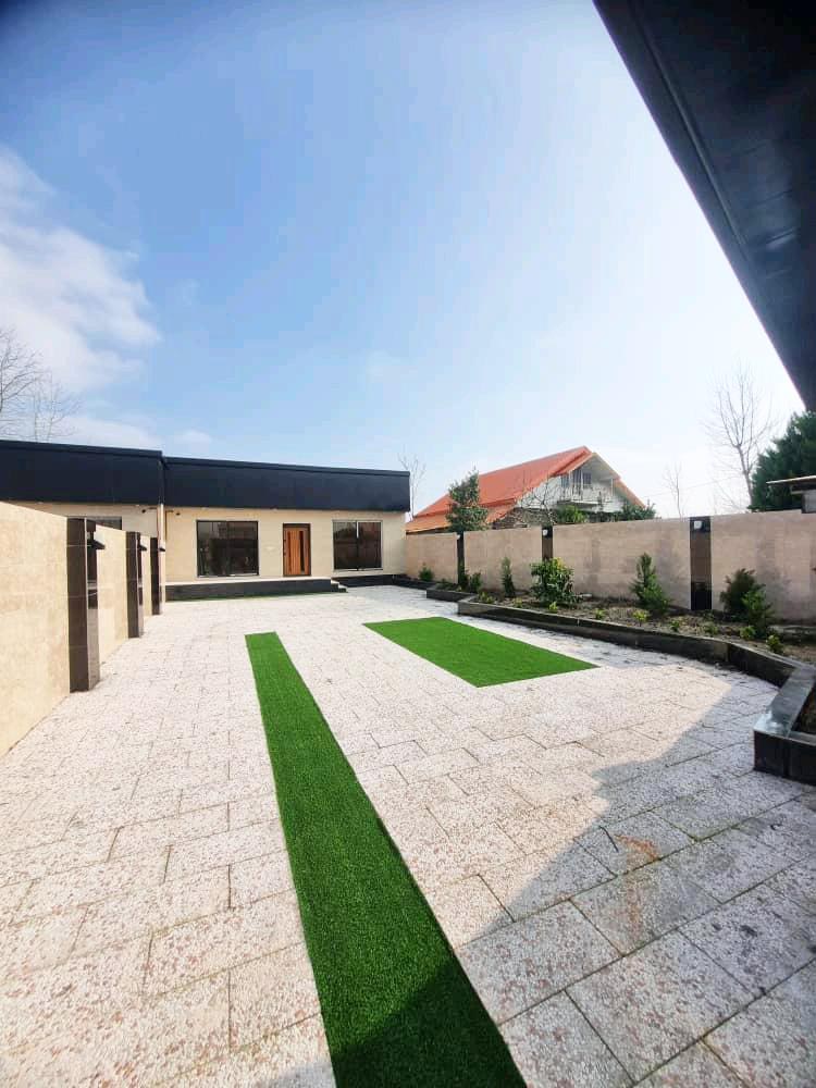 تصویر یک ویلای فلت روستایی که محوطه سازی شده و از چمن مصنوعی استفاده شده