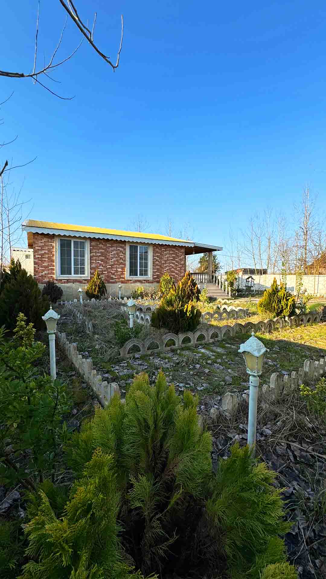 تصویر یک ویلای فلت روستایی که محوطه سازی شده و از چمن مصنوعی استفاده شده