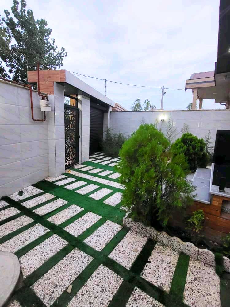 تصویر یک ویلای نما مدرن و محوطه سازی شده با موزاییک و چمن مصنوعی