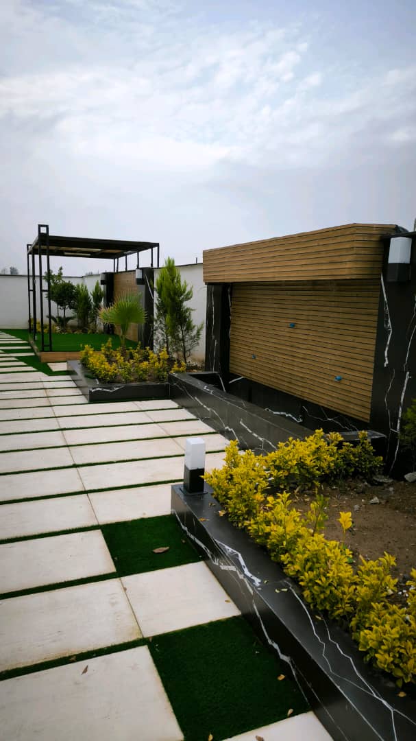 تصویر یک ویلای نما مدرن و محوطه سازی شده با موزاییک و چمن مصنوعی