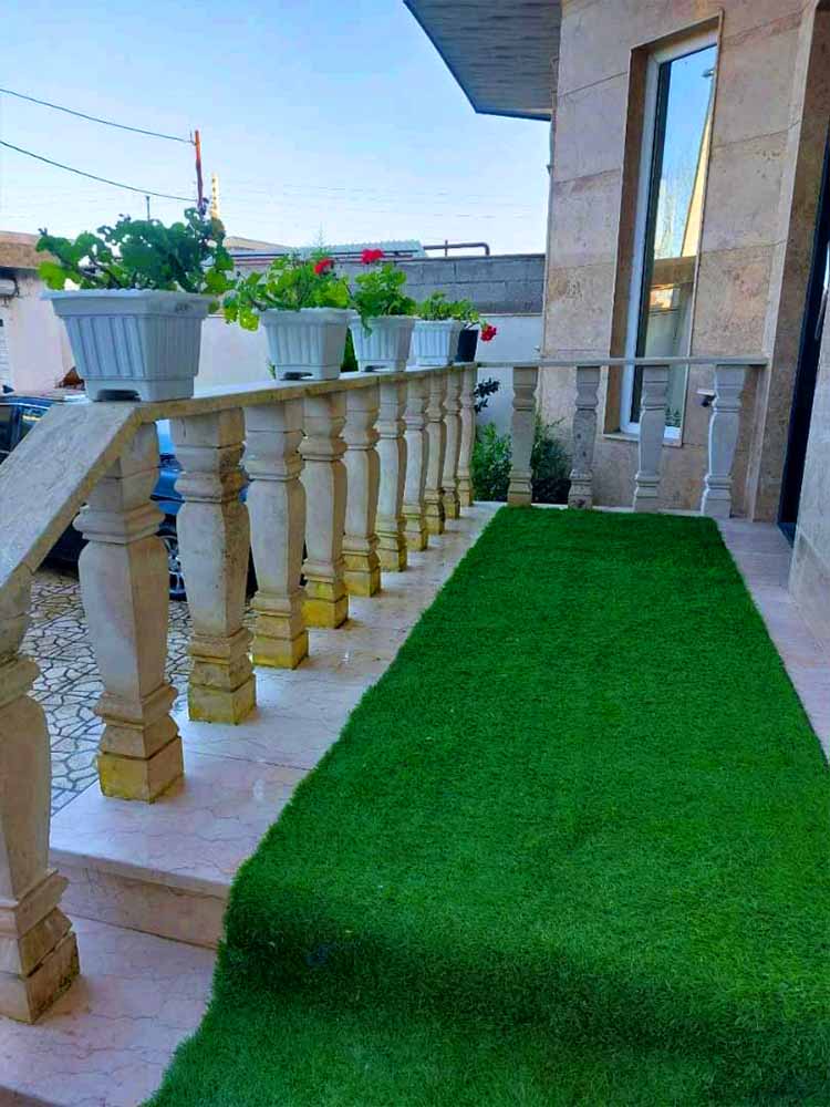 تصویر یک ویلای فلت روستایی که محوطه سازی شده و از چمن مصنوعی استفاده شده