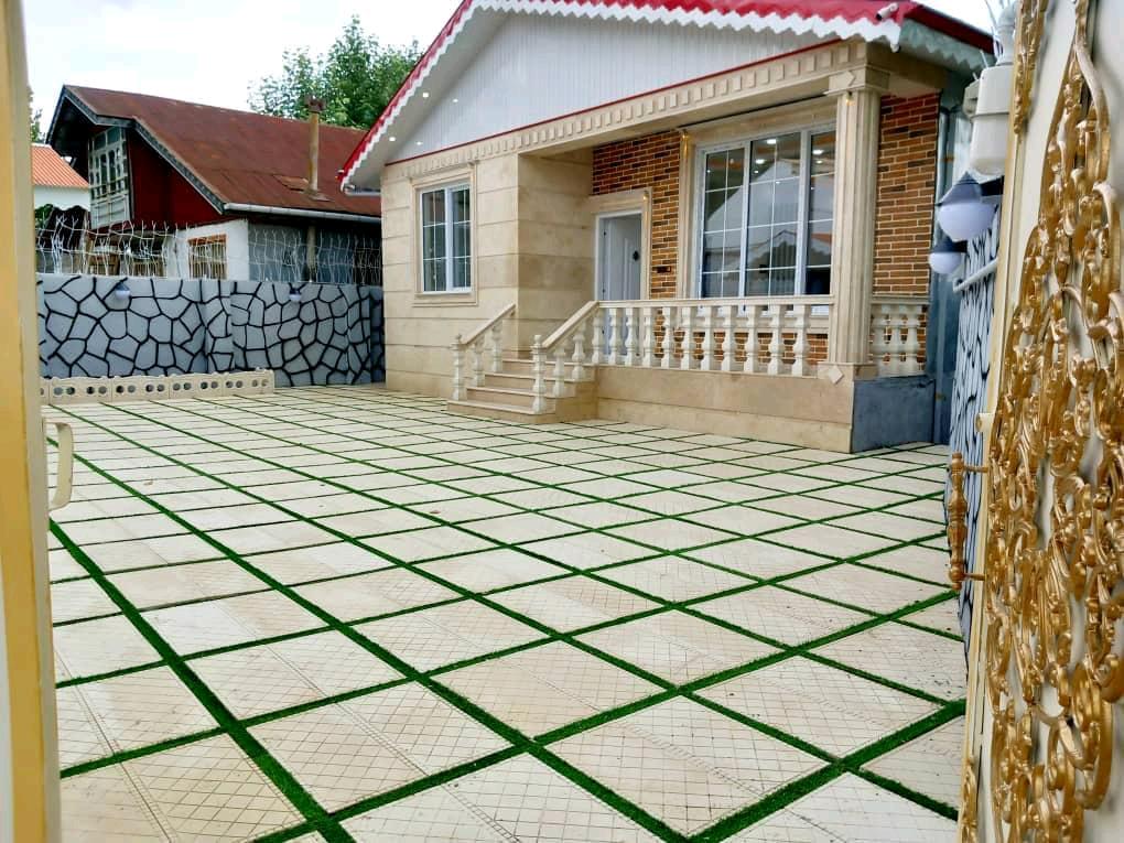 تصویر یک ویلای فلت روستایی که محوطه سازی شده و از چمن مصنوعی استفاده شده